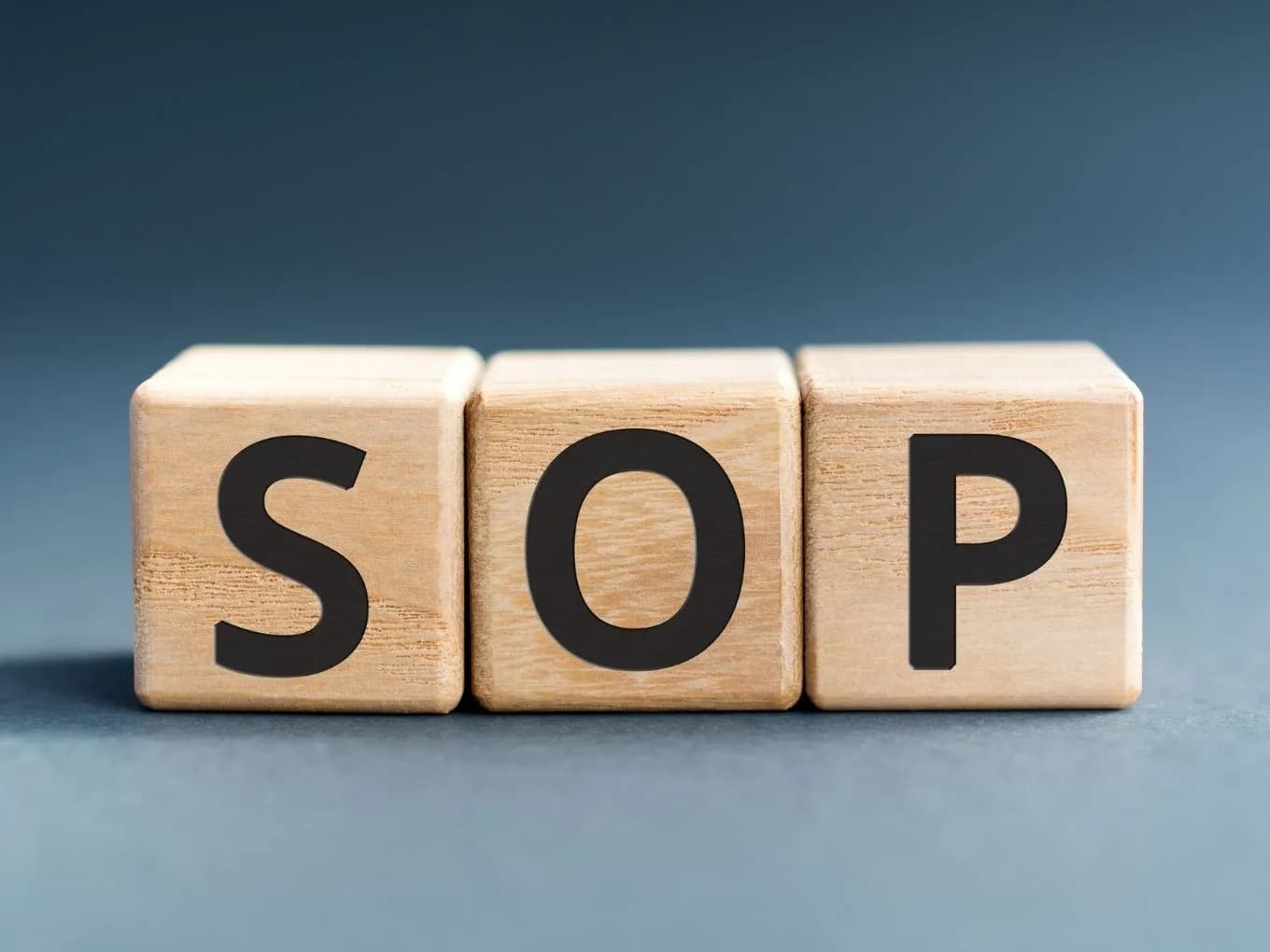 Three wood letter blocks spelling S O P