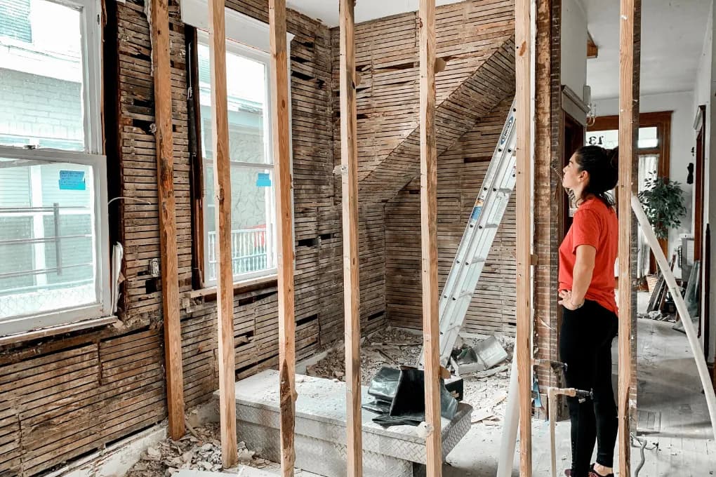 woman in red shirt assessing home for fix and flip project