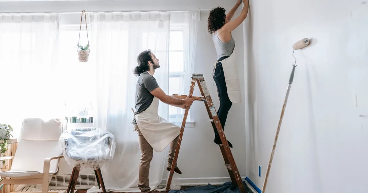 Two people painting walls in a renovated home.