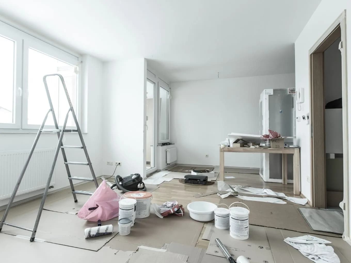 Interior of a house with construction materials all round. Paint, ladders, cardboard.