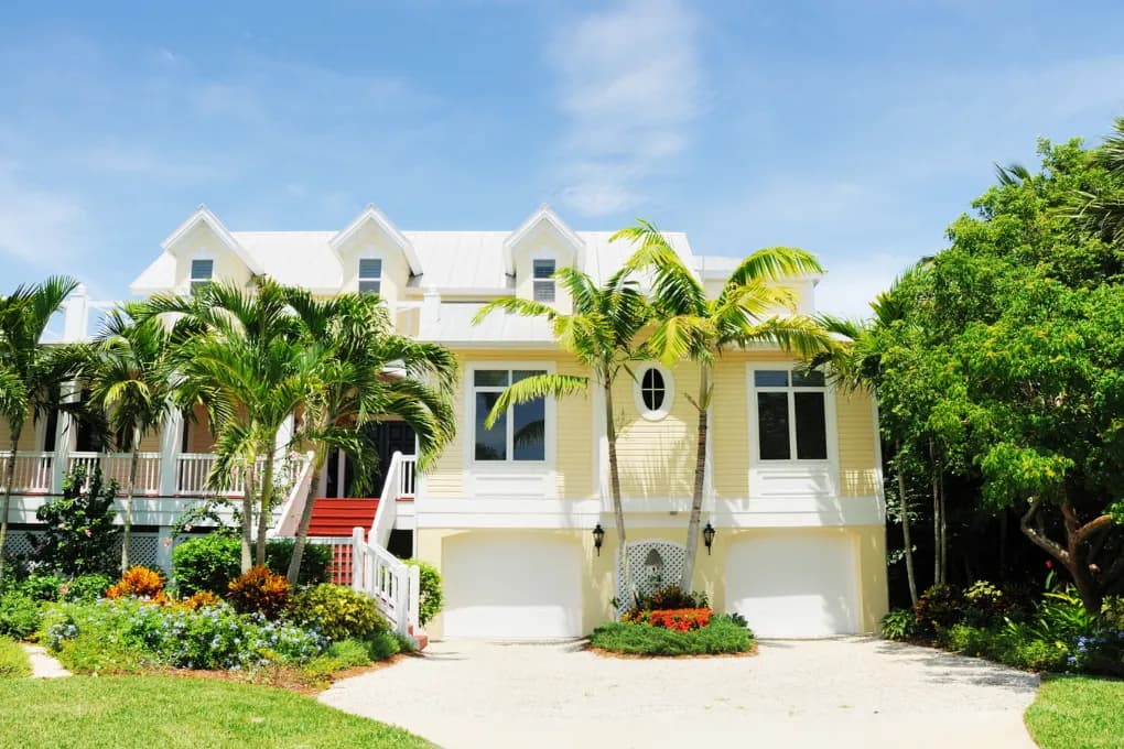 exterior image of yellow house with palm trees in front
