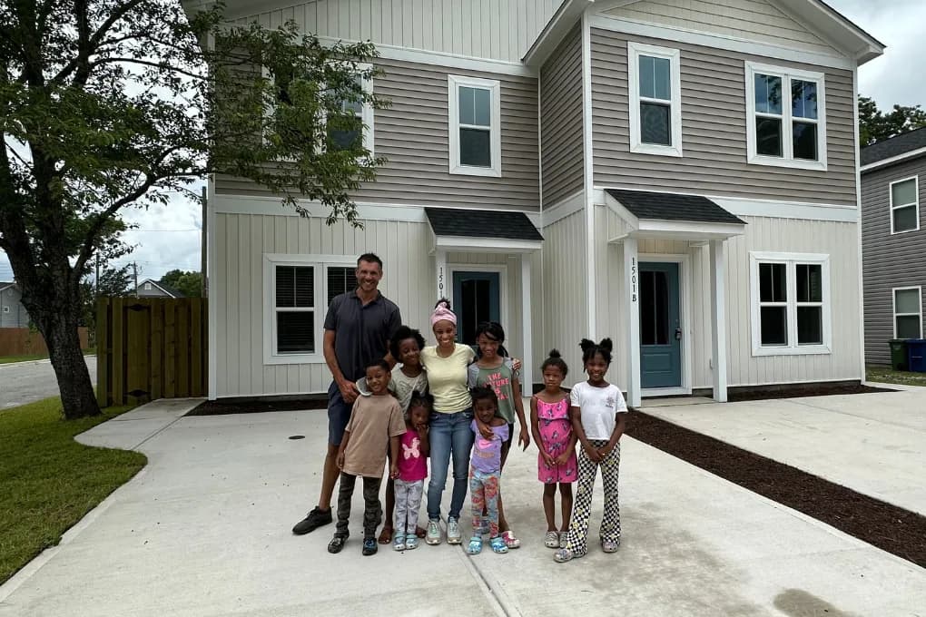 man and woman with children standing in front of new construction home