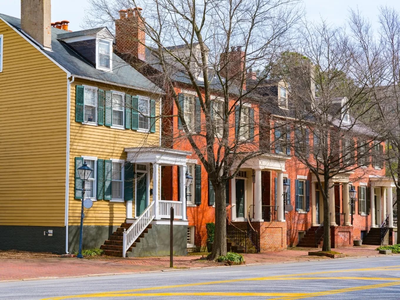 four two story houses surrounded by trees. colors from left to rigth yellow orange red red